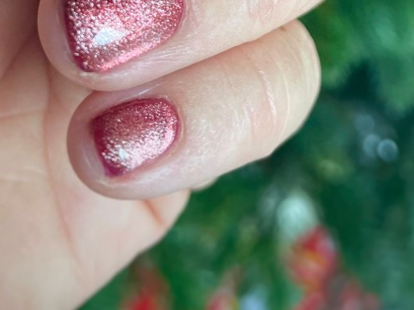 Close-up van twee korte nagels met een roze cat eye vol glitter