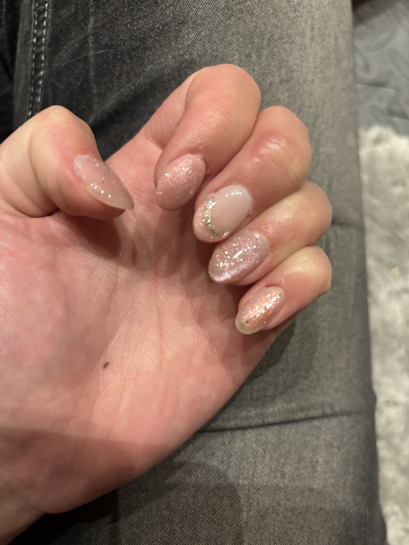 Nude amandelnagels met glitter en een lijntje parels op de ringvinger